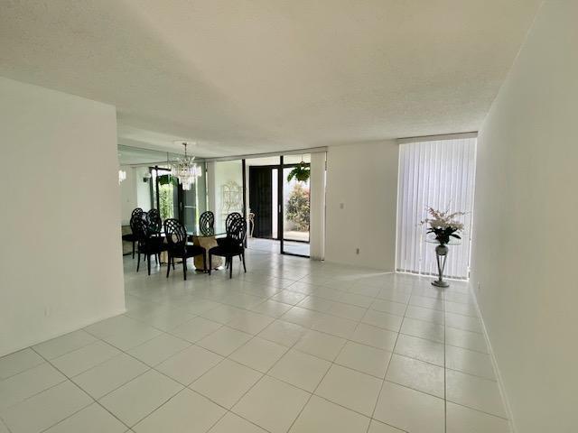 spare room with light tile floors, a notable chandelier, a textured ceiling, and a wall of windows