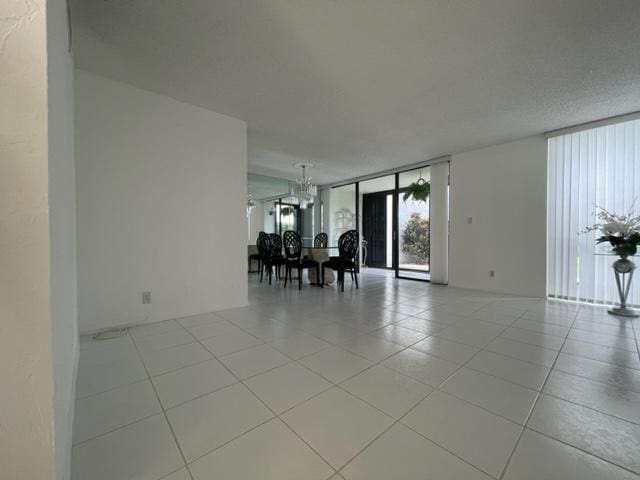 tiled spare room with a chandelier and floor to ceiling windows