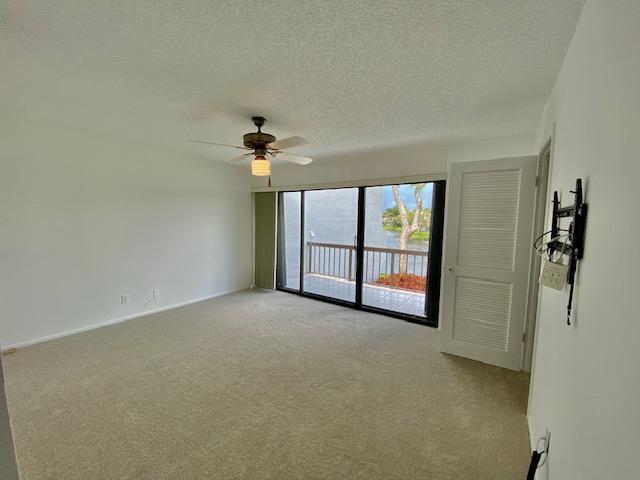 carpeted spare room with a textured ceiling and ceiling fan