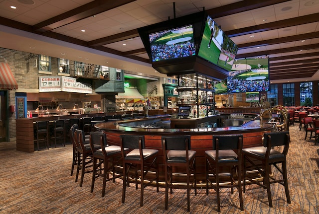 bar with dark carpet and beamed ceiling