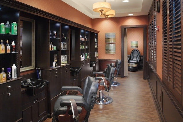 bar with a raised ceiling, dark brown cabinets, and light hardwood / wood-style flooring