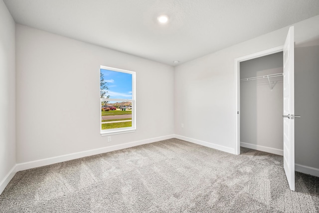 unfurnished bedroom with a closet and light colored carpet