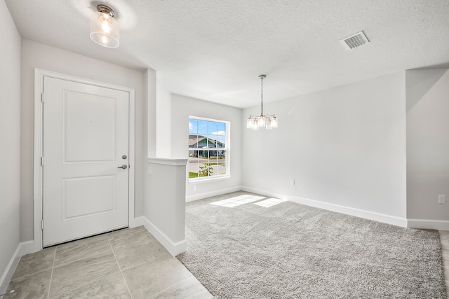 carpeted entrance foyer featuring a textured ceiling and an inviting chandelier