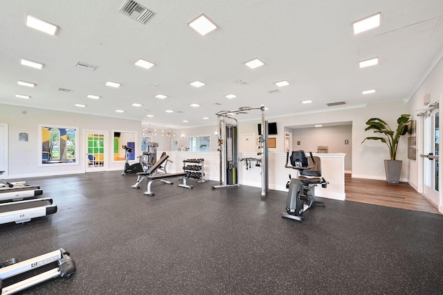 exercise room featuring a textured ceiling, crown molding, and dark hardwood / wood-style floors