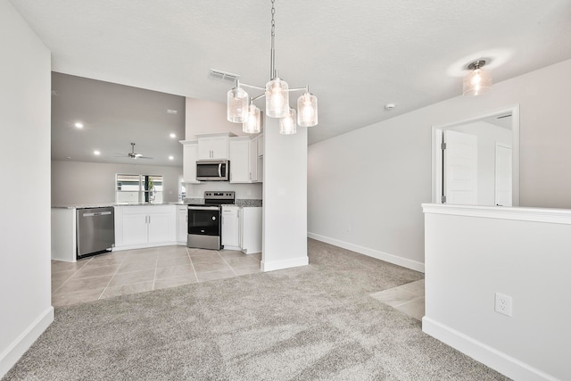 kitchen featuring hanging light fixtures, ceiling fan, stainless steel appliances, white cabinets, and light colored carpet