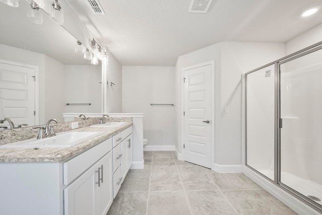 bathroom featuring an enclosed shower, dual vanity, tile flooring, and toilet