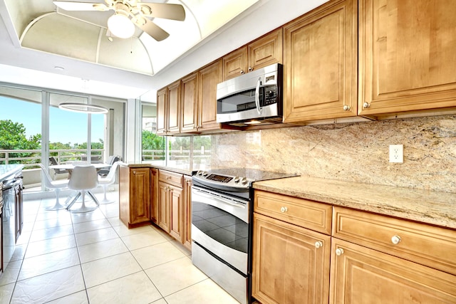 kitchen with ceiling fan, light tile patterned floors, appliances with stainless steel finishes, light stone countertops, and decorative backsplash