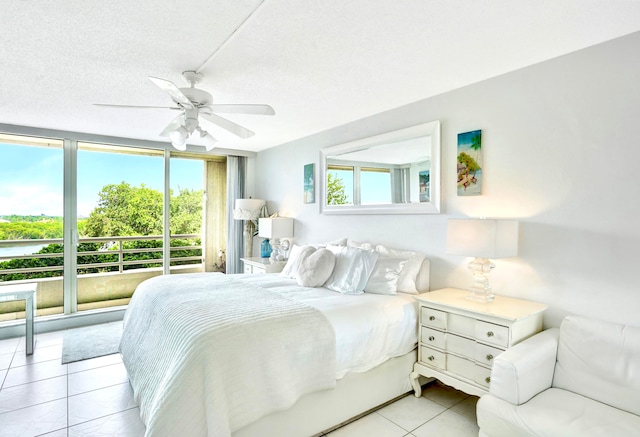 bedroom featuring multiple windows, light tile patterned flooring, ceiling fan, and a textured ceiling