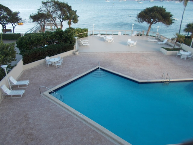 view of swimming pool featuring a patio area and a water view