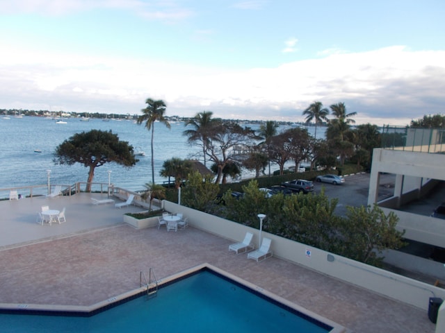 view of pool with a water view and a patio