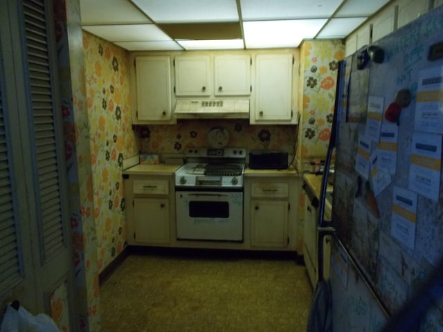 kitchen with white stove, ventilation hood, a drop ceiling, and fridge