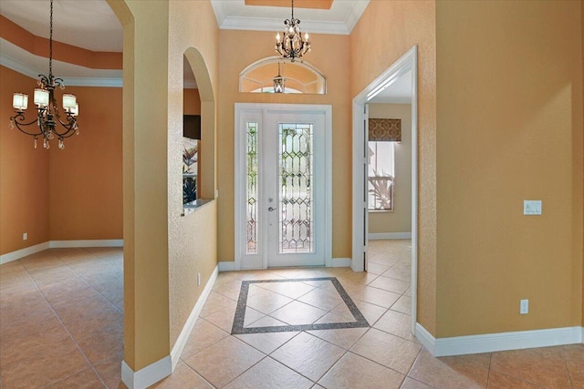 foyer entrance featuring an inviting chandelier, light tile patterned floors, and ornamental molding