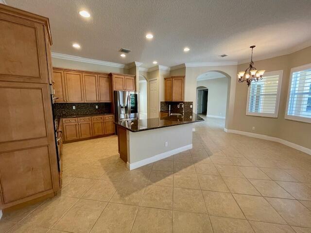 kitchen with light tile patterned floors, ornamental molding, stainless steel fridge with ice dispenser, decorative backsplash, and decorative light fixtures