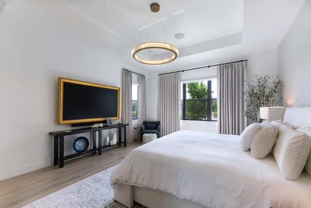 bedroom with hardwood / wood-style floors and a raised ceiling