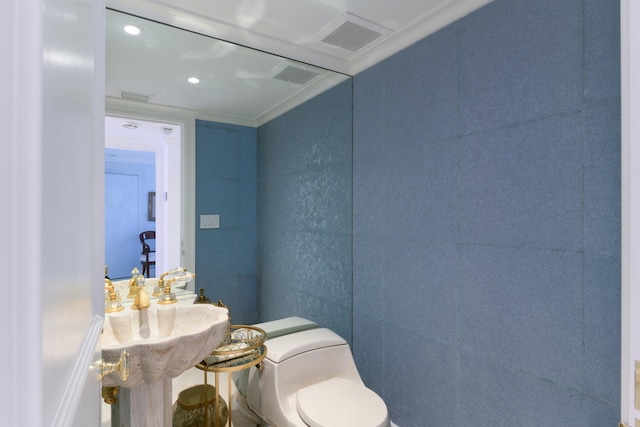 bathroom with toilet, crown molding, and tile walls