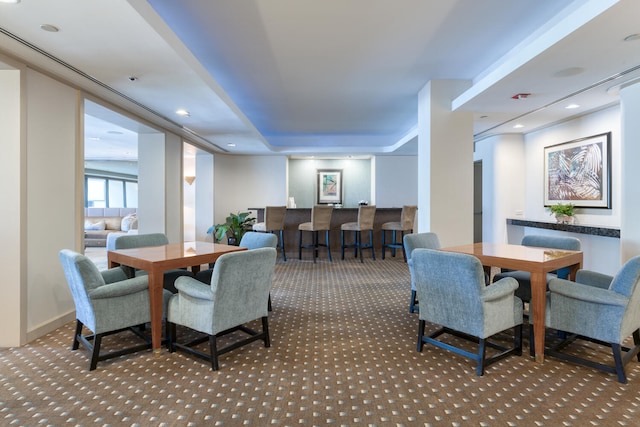 carpeted dining room with a tray ceiling