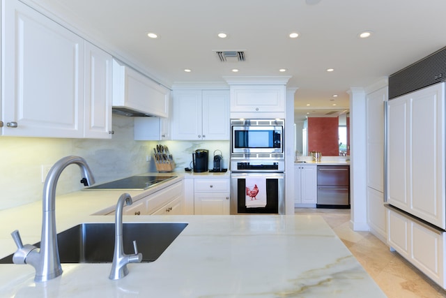 kitchen featuring black electric stovetop, double oven, backsplash, light stone countertops, and white cabinets