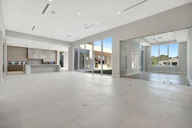 unfurnished living room featuring ceiling fan and plenty of natural light