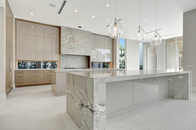 kitchen featuring pendant lighting, light brown cabinets, tasteful backsplash, a large island, and light stone counters