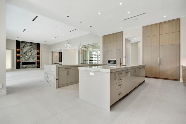 kitchen featuring a large island with sink, light brown cabinetry, and sink