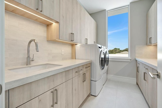 laundry area featuring cabinets, light tile patterned floors, washing machine and dryer, and sink