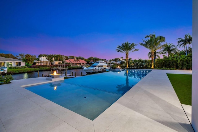 pool at dusk featuring a water view