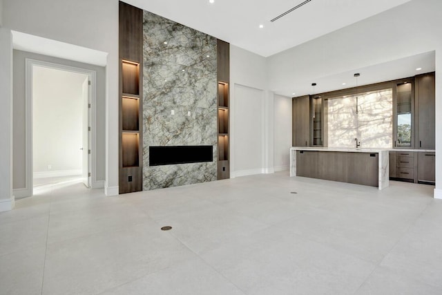 unfurnished living room featuring a large fireplace, a towering ceiling, and sink