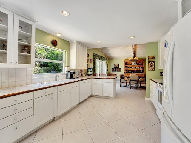 kitchen with light tile flooring, white appliances, white cabinetry, backsplash, and tile counters