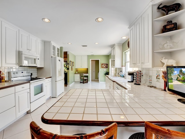 kitchen with backsplash, white cabinetry, white appliances, and tile countertops