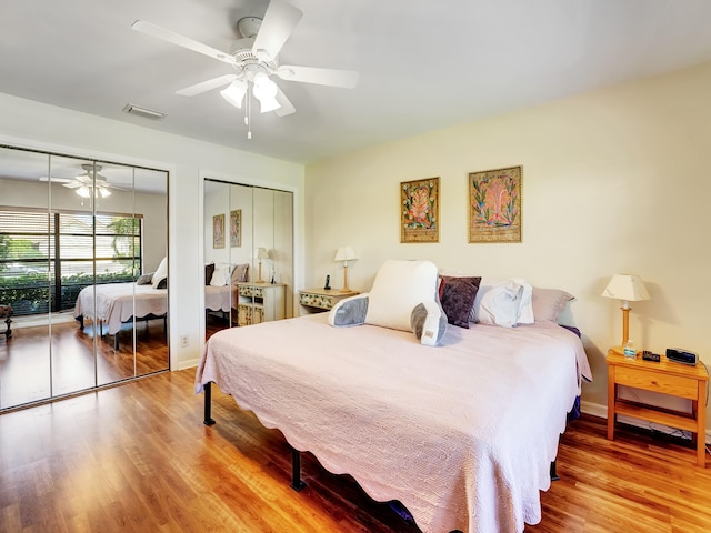 bedroom with ceiling fan, light hardwood / wood-style floors, and multiple closets