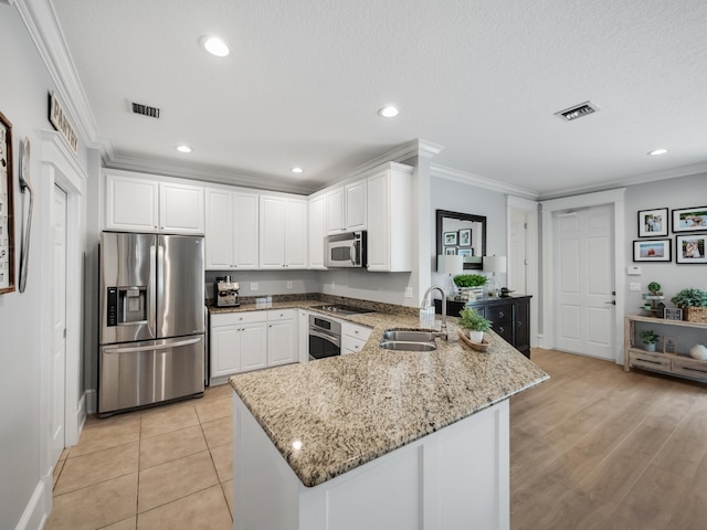 kitchen with appliances with stainless steel finishes, sink, kitchen peninsula, white cabinets, and crown molding