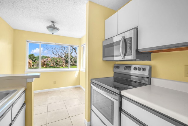 kitchen featuring white cabinets, a textured ceiling, light tile floors, and appliances with stainless steel finishes