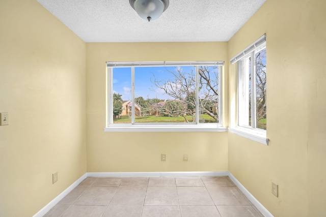 spare room featuring light tile floors and a textured ceiling