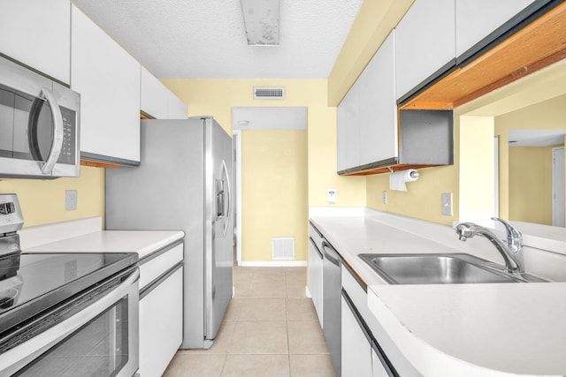 kitchen featuring a textured ceiling, stainless steel appliances, white cabinetry, and sink