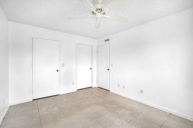 unfurnished bedroom with a textured ceiling, light tile flooring, and ceiling fan