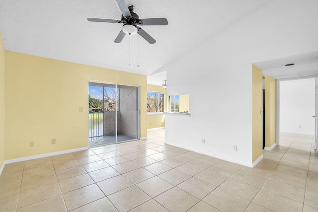 spare room featuring light tile floors, a textured ceiling, high vaulted ceiling, and ceiling fan