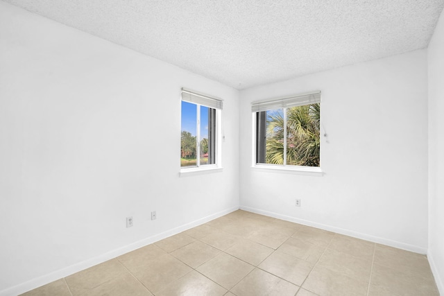 unfurnished room with light tile floors and a textured ceiling