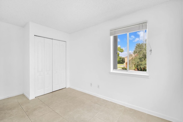 unfurnished bedroom with a closet, a textured ceiling, and light tile flooring