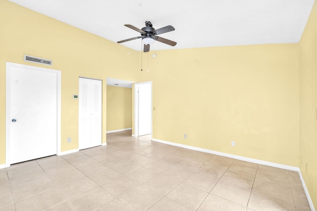 spare room with light tile floors, high vaulted ceiling, and ceiling fan