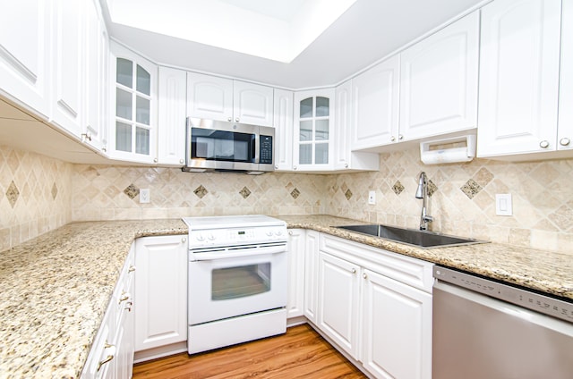 kitchen featuring white cabinets, backsplash, appliances with stainless steel finishes, light hardwood / wood-style flooring, and sink