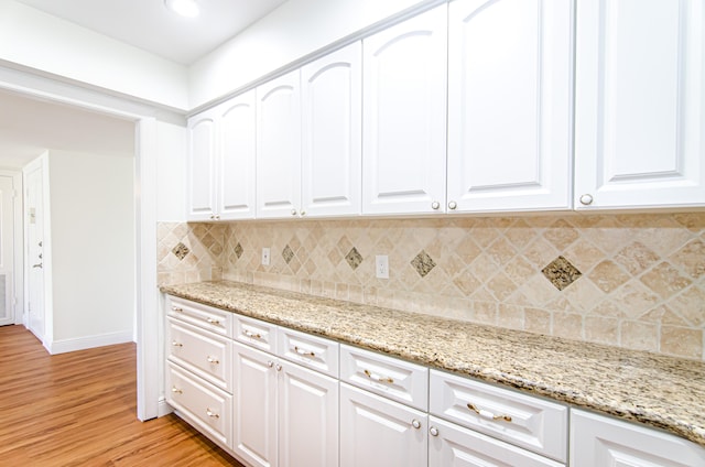 kitchen featuring white cabinetry, light stone counters, and light hardwood / wood-style flooring