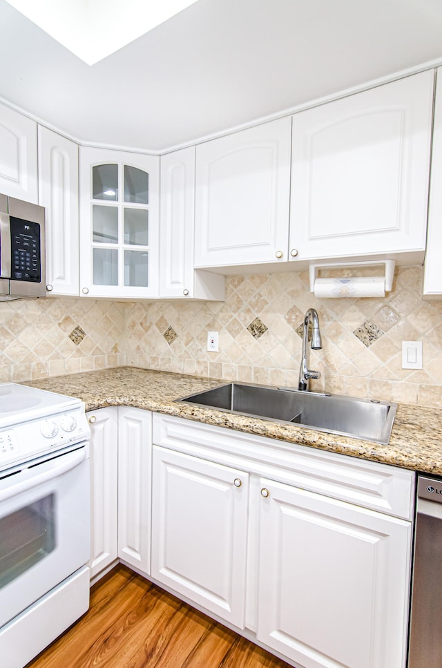 kitchen with decorative backsplash, hardwood / wood-style flooring, sink, white electric stove, and white cabinetry