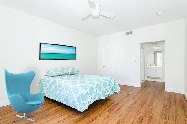 bedroom featuring a closet, hardwood / wood-style floors, ensuite bath, and ceiling fan