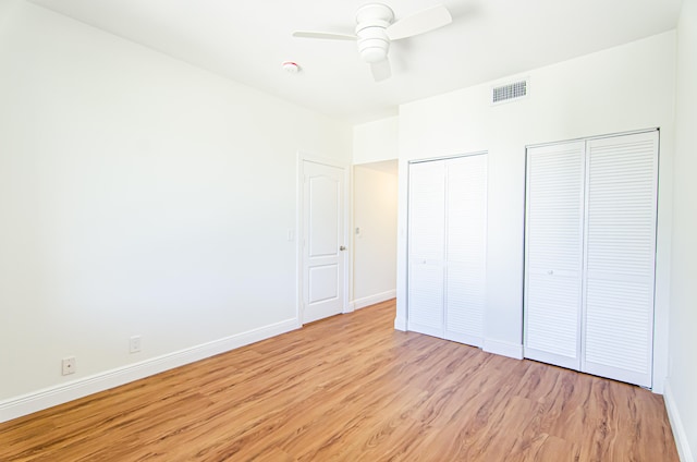 unfurnished bedroom featuring light hardwood / wood-style flooring, multiple closets, and ceiling fan