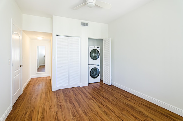 laundry room featuring ceiling fan, wood-type flooring, and stacked washer and dryer