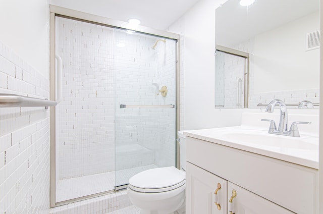 bathroom with vanity, toilet, walk in shower, and tile walls