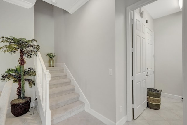 staircase with ornamental molding and light tile floors