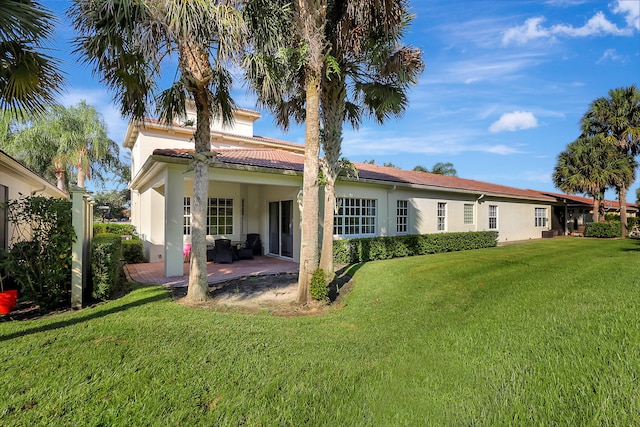 back of property with a lawn and a patio