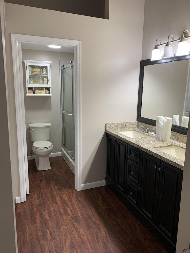 bathroom featuring hardwood / wood-style flooring, vanity, a shower with shower door, and toilet