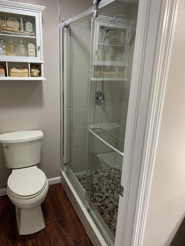 bathroom featuring hardwood / wood-style floors, a shower with door, and toilet